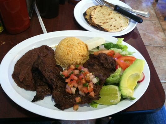 Grilled carne asada plate with rice, salad, avocado, and pico de gallo